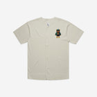 A bone-colored baseball jersey featuring a vibrant, embroidered bear patch on the chest, combining sporty style with a playful and unique detail.