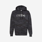 A black camouflage print hoodie with the text "[‘TEEN]" printed in bold white lettering across the chest. The design blends subtle camo tones with a sleek streetwear aesthetic.