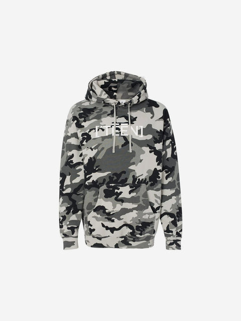 A gray and white snow camouflage print hoodie with "[‘TEEN]" printed in bold white text across the chest. This hoodie showcases a striking pattern perfect for a cool, edgy look.