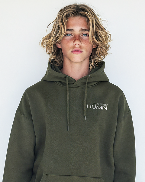 A blonde-haired teenage boy wearing an olive hoodie with the minimalistic LITTLE HUMN logo on the chest. The design highlights a clean, eco-conscious vibe for casual wear.